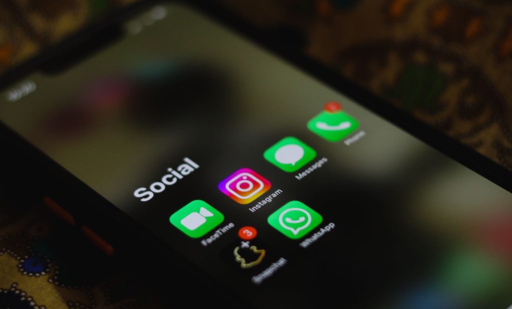 Mão segurando um celular com redes sociais abertas